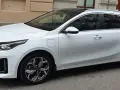 Vit Kia Ceed SW Plug-in Hybrid parkerad på gata. En elsparkcykel syns i bakgrunden.