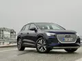 Mörkblå Audi Q4 e-tron på en väg med en bro i bakgrunden. En del av en audi q4 e-tron test.
