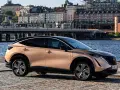 Nissan Ariya testkörning i Stockholm. En elegant elbil parkerad vid vattnet med stadens silhuett i bakgrunden.
