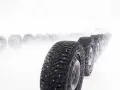 Vinterdäck i rad, redo för gislaved nordfrost 200 test i snöstorm. En bil skymtar i fjärran.