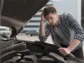 Man med bekymrat ansikte tittar ner i motorhuvens öppning. Han verkar fundera på varför bilen låter konstigt vid tomgång.
