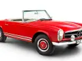 Röd cabriolet, en klassisk Mercedes 230 SL, med kromdetaljer och vit interiör.