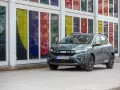 Grön Dacia Sandero Stepway, redo för ett däcktest. Bilen står parkerad framför en byggnad med färgglada fönster.