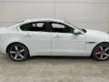 Vit Jaguar XE, sidovy. En bil med ett potentiellt jaguar xe problem, står parkerad på ett betonggolv.
