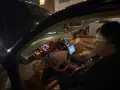 Personen försöker starta bilen, men den startar inte, bara klickar. Motorhuven är öppen och en laptop är på passagerarsätet.