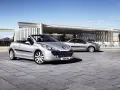 Två silverfärgade Peugeot 207 CC cabriolet står parkerade på en stenlagd uteplats framför en modern byggnad.