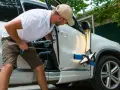 Man fixar en buckla på bilen med specialverktyg och ljus.