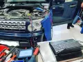 Diagnostik av Land Rover med öppen motorhuv. Kablar kopplade till motor och en dator för felsökning av jordfel bil symtom.