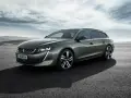 Grå Peugeot 508 SW står parkerad på en asfalterad yta med berg i bakgrunden. En perfekt bil för ett peugeot 508 test.
