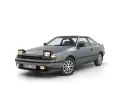 Grå Toyota Celica 1986 med pop-up-strålkastare, redo för en nostalgisk resa.