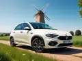 Vit Fiat Tipo står vid en grusväg med en väderkvarn i bakgrunden. Kanske ett litet fiat tipo problem med att hitta rätt väg?