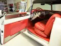 En vit cabriolet Cadillac från 50-talet med lyxig röd interiör. Dörren är öppen och visar upp säten och instrumentbräda.