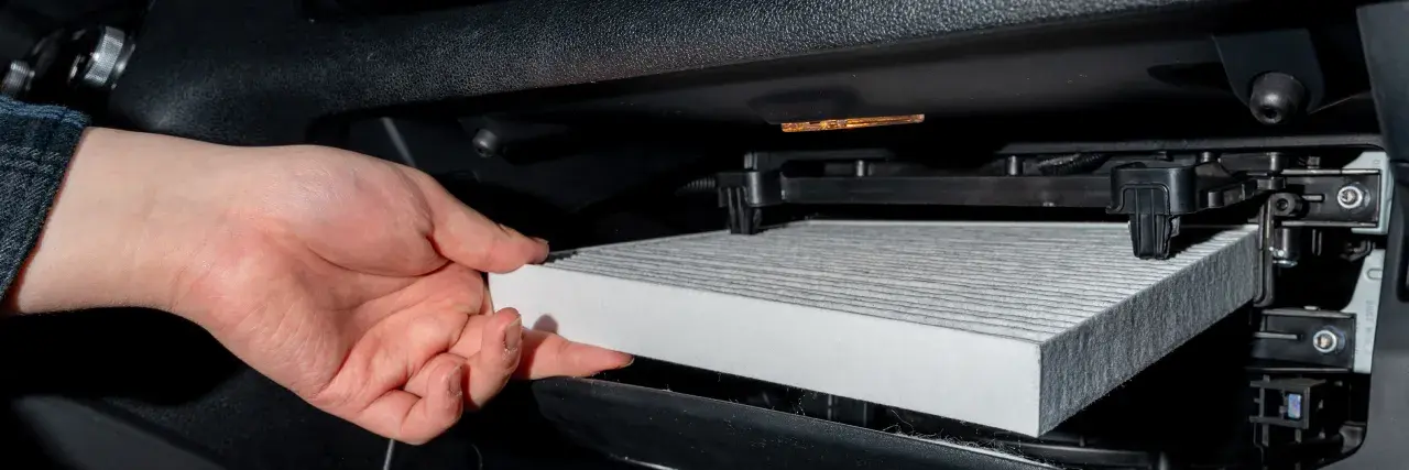Hand byter ett nytt kupéfilter. Frågan är hur ofta byta kupefilter för ren luft i bilen.