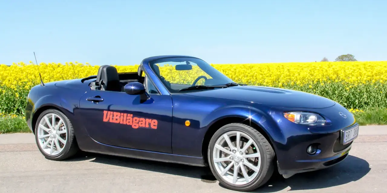 Blå Mazda MX-5 cabriolet parkerad vid en gul rapsåker. Ett potentiellt Mazda MX-5 problem kan vara att den drar till sig uppmärksamhet.
