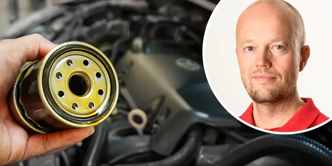 En hand håller ett oljefilter, redo att byta det för att stoppa vobblande ljud från bilen. En man i rött syns i bakgrunden.