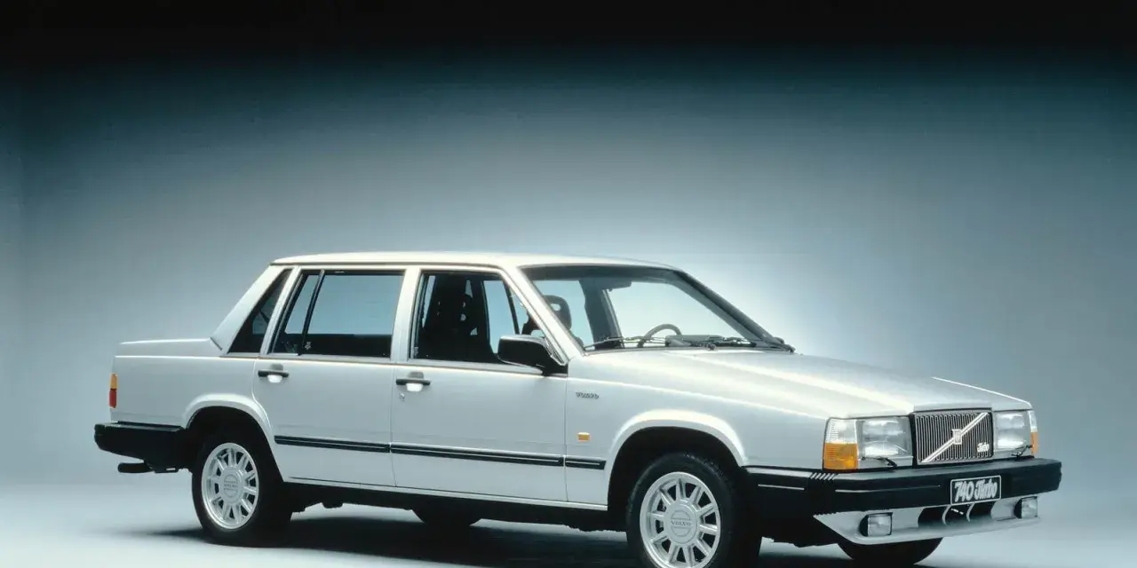 En silverfärgad, gammal Volvo 740 Turbo står uppställd i studio. Bilen har en klassisk design med raka linjer och en distinkt grill.