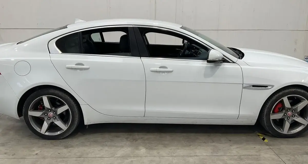 Vit Jaguar XE, sidovy. En bil med ett potentiellt jaguar xe problem, står parkerad på ett betonggolv.