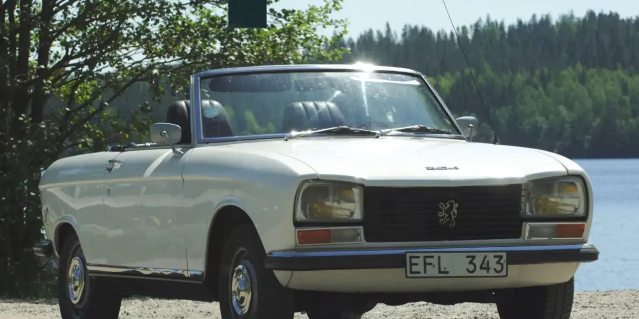 Vit cabriolet Peugeot 304 står vid en sjö.