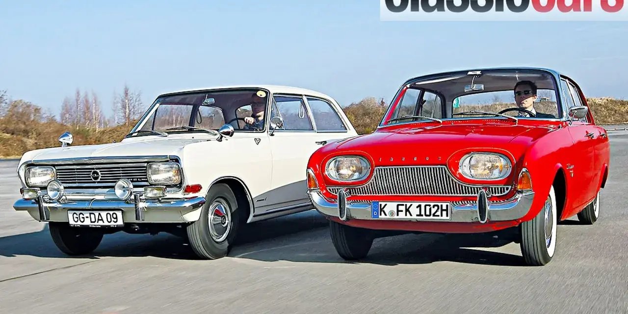 Två klassiska bilar, en vit och en röd, kör på en väg. Den röda bilen är en Ford Taunus från 1960.
