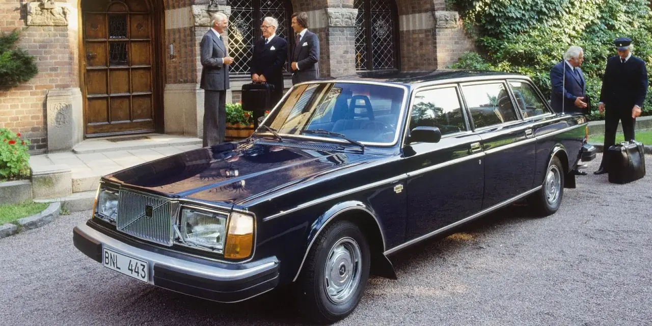 Mörkblå Volvo 264 Bertone limousine parkerad framför en byggnad med män i kostym.