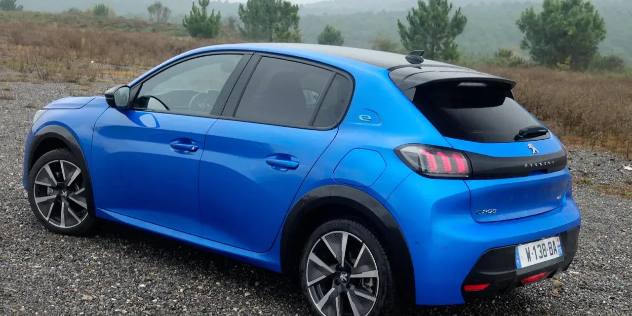Blå Peugeot e-208 GT på grusväg. En elbil redo för peugeot e-208 test i naturen.