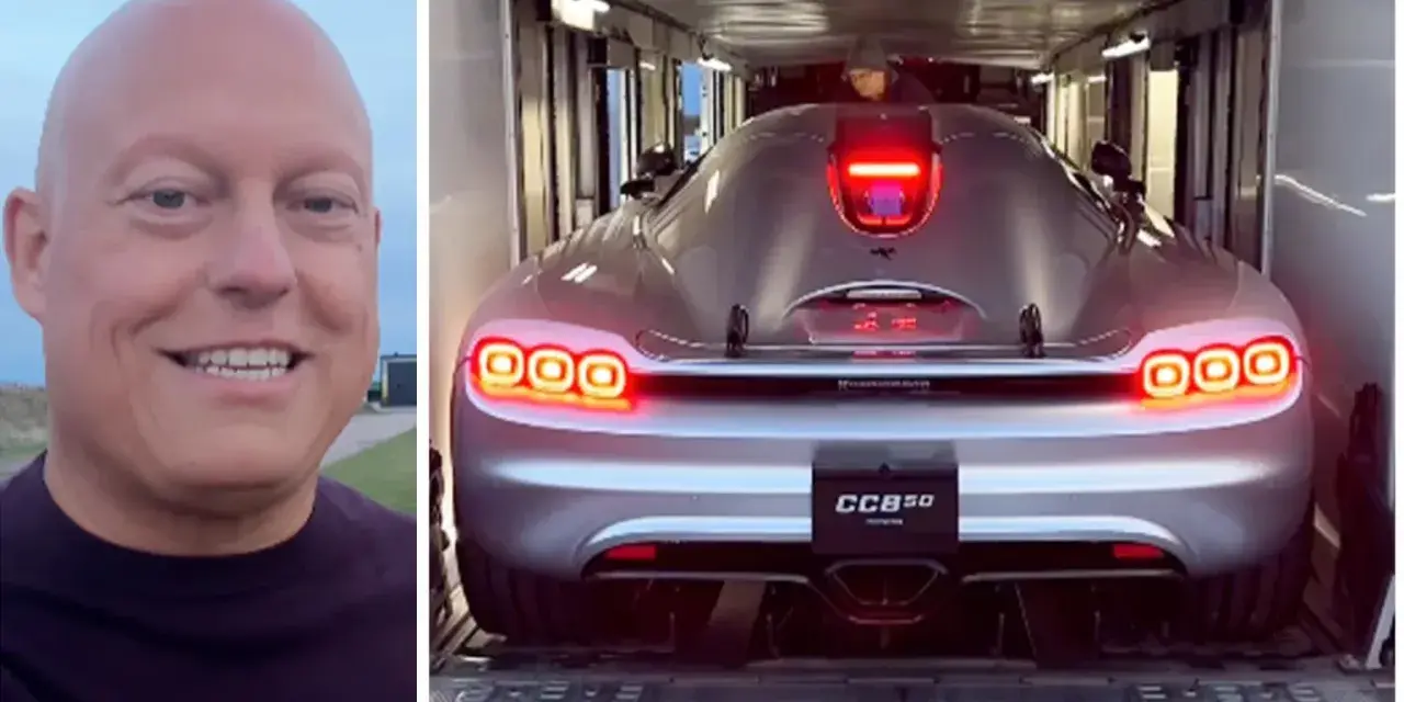 En man ler bredvid en silverfärgad Koenigsegg CC850 som lastas in i en trailer.