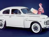 En elegant vit Volvo PV 444 med en kvinna och en hund bredvid.