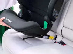 En person monterar en Maxi-Cosi bilbarnstol utan isofix i en bil. Barnstolen placeras på bilsätet och fästs med bilens säkerhetsbälte.