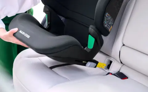 En person monterar en Maxi-Cosi bilbarnstol utan isofix i en bil. Barnstolen placeras på bilsätet och fästs med bilens säkerhetsbälte.