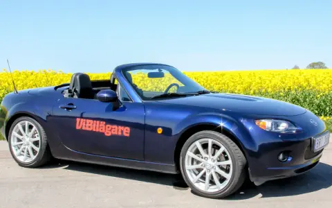 Blå Mazda MX-5 cabriolet parkerad vid en gul rapsåker. Ett potentiellt Mazda MX-5 problem kan vara att den drar till sig uppmärksamhet.