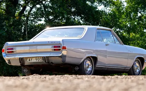 En grå Opel Diplomat coupé står parkerad utomhus.