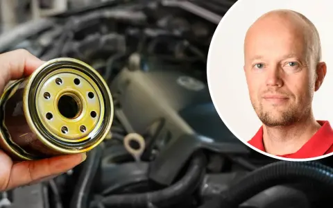 En hand håller ett oljefilter, redo att byta det för att stoppa vobblande ljud från bilen. En man i rött syns i bakgrunden.
