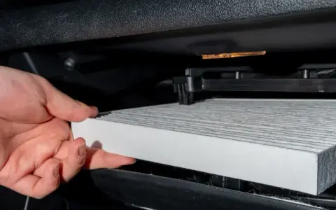Hand byter ett nytt kupéfilter. Frågan är hur ofta byta kupefilter för ren luft i bilen.