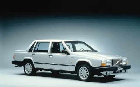 En silverfärgad, gammal Volvo 740 Turbo står uppställd i studio. Bilen har en klassisk design med raka linjer och en distinkt grill.