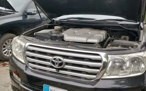 Motorhuven på en svart p0420 Toyota Land Cruiser är öppen, vilket visar V8-motorn. En annan likadan bil står bredvid.
