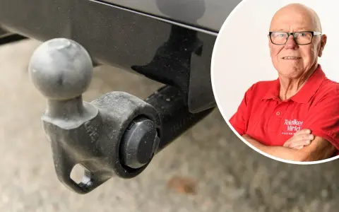 En man i röd tröja med texten "Tekniker Värld" ler, bredvid en bil med dragkrok. Dags att ta bort dragkrok?