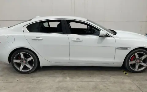 Vit Jaguar XE, sidovy. En bil med ett potentiellt jaguar xe problem, står parkerad på ett betonggolv.