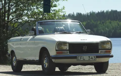Vit cabriolet Peugeot 304 står vid en sjö.