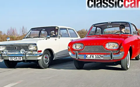 Två klassiska bilar, en vit och en röd, kör på en väg. Den röda bilen är en Ford Taunus från 1960.