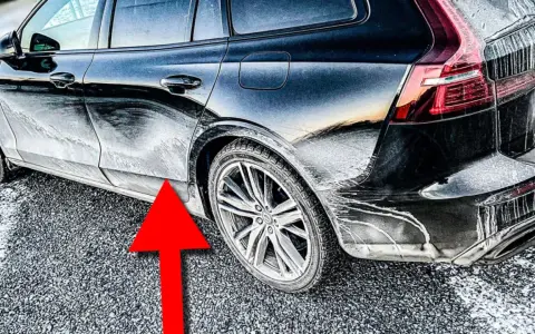 En mörk bil täckt av frost och smuts. En röd pil pekar mot en rostig bil.