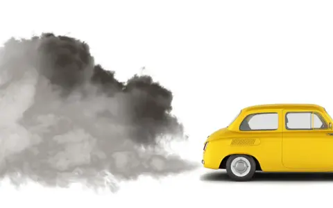 En gul retrobil släpper ut en stor rökpuff. Det luktar avgaser i bilen, en tydlig miljöbild.