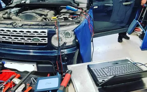 Diagnostik av Land Rover med öppen motorhuv. Kablar kopplade till motor och en dator för felsökning av jordfel bil symtom.