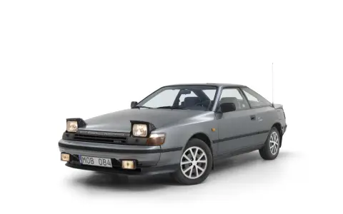 Grå Toyota Celica 1986 med pop-up-strålkastare, redo för en nostalgisk resa.