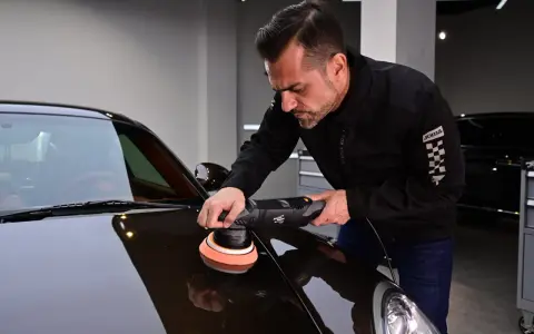 Man använder polermaskin för att polera bilen till perfektion.