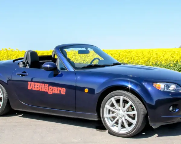 Blå Mazda MX-5 cabriolet parkerad vid en gul rapsåker. Ett potentiellt Mazda MX-5 problem kan vara att den drar till sig uppmärksamhet.