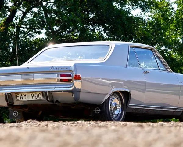 En grå Opel Diplomat coupé står parkerad utomhus.