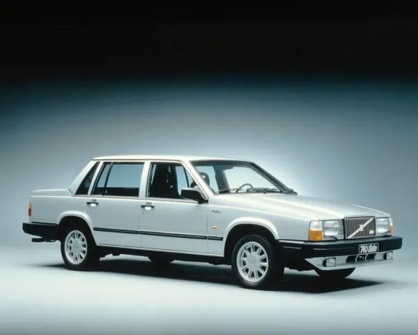 En silverfärgad, gammal Volvo 740 Turbo står uppställd i studio. Bilen har en klassisk design med raka linjer och en distinkt grill.