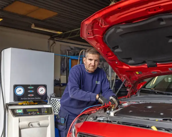 Mekaniker arbetar med bilens AC-system. Lär dig hur fungerar ac i bilen med denna serviceutrustning.