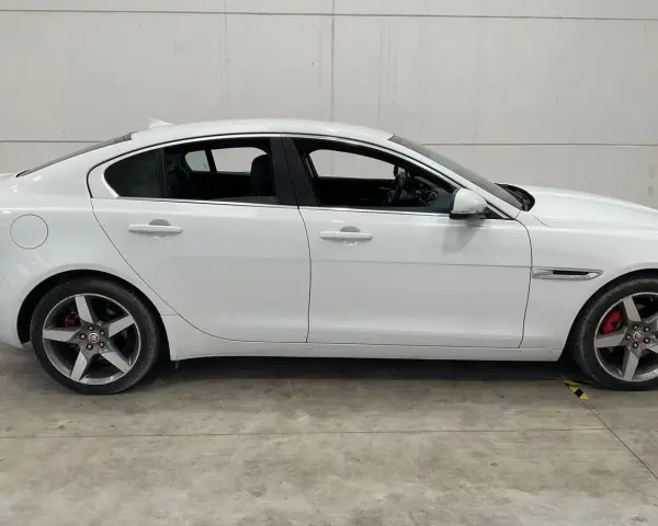Vit Jaguar XE, sidovy. En bil med ett potentiellt jaguar xe problem, står parkerad på ett betonggolv.