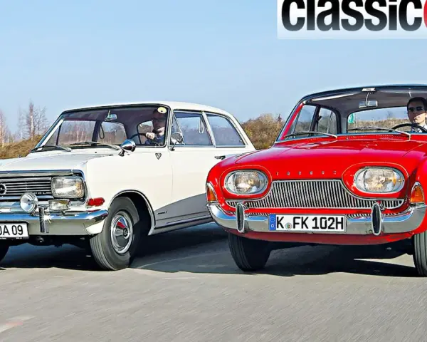 Två klassiska bilar, en vit och en röd, kör på en väg. Den röda bilen är en Ford Taunus från 1960.